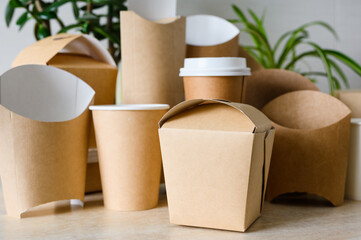 Container for noodles on a background of disposable tableware. Disposable tableware and paper packaging. Selective focus on noodle container.