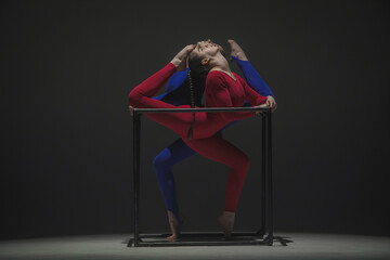 Portrait of two female acrobats isolated on black background. Girls aerial dancers in blue red...