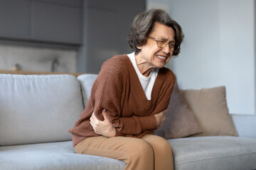 Senior woman touching belly, suffering from stomachache, food poisoning, gastritis, abdominal pain,...