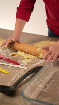 manos de niño vestido de rojo amasando harina y preparado la masa hornear galletas o pan casero con utensilios de cocina usando rodillo para preparar