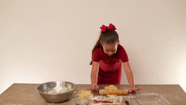 ni&ntilde;a latina feliz preparando galletas caseras con harina de trigo y masa usando utensilios de cocina platos rodillo mesa cucharas para hornear pastel y compartir