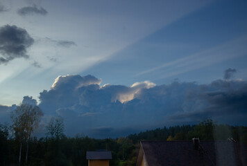 Naklejka na ściany i meble Clouds in the blue sky at sunset. Natural background and texture. Clouds over the village in the evening. Ornamental clouds. Dramatic sky. Epic storm cloudscape. Soft sunlight. Panoramic image,