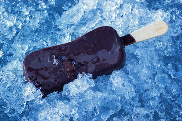 One ice cream on wooden stick coated with chocolate glaze. Cold dessert on natural ice crystals.