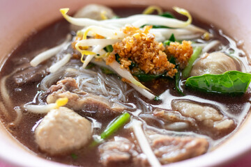 Rice vermicelli noodles with stewed beef sliced, meatball and vegetables in a bowl. Thai style beef noodle soup.
