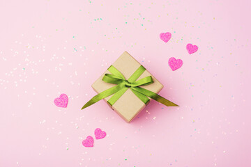 Gift box with green ribbon, pink hearts and confetti decorations. Valentines day concept. Top view, flat lay
