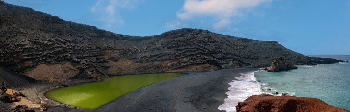 Stunning view of the imploded volcano caldera on the shores of the island of Lanzarote, Canary Islands. On the left the green lagoon at the center of the volcano