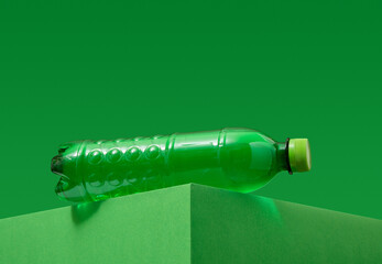 Green plastic water bottle on a green background. Copy space for text.