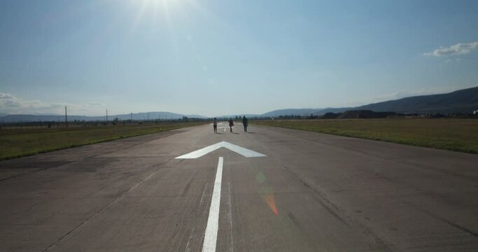 three people walking and taking pictures on an airport runway