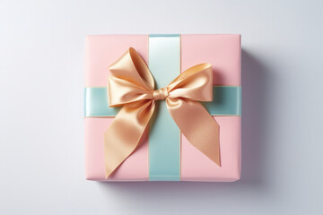 A top view of an elegant gift box wrapped in pink and blue paper, adorned with a shiny golden ribbon, presented on a clean white background