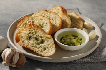 Tasty baguette with garlic and dill served on grey textured table