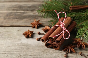 Different spices and fir branches on wooden table, space for text