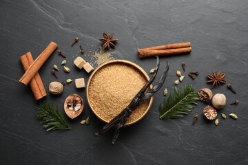 Different aromatic spices and fir branches on dark textured table, flat lay