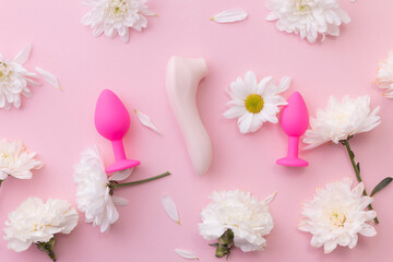 Different set sex toys for woman on pink background with flowers, top view