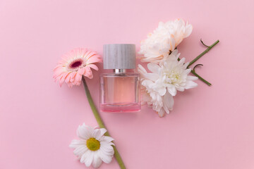 Perfume bottle amidst white flowers on pink surface Flat lay. Concept spring aroma water for skincare