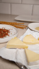 Preparing Camembert Christmas trees: pieces of cheese, salt-dusted straws, honey, and spices on the table—a festive New Year's snack
