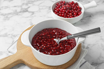 Fresh cranberry sauce in bowl served on white marble table, closeup
