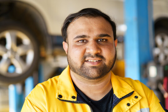 A senior vehicle technician posing for a photograph in the garage.  - Powered by Adobe