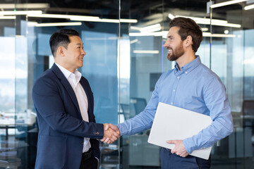 Professional and friendly handshake between two businessmen in an office setting, symbolizing...