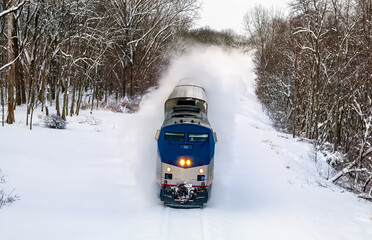 Amtrak passenger train in deep snow banking slightly through a high speed turn in Michigan - obrazy, fototapety, plakaty