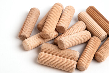 Pile of wooden dowels on the white background. - obrazy, fototapety, plakaty