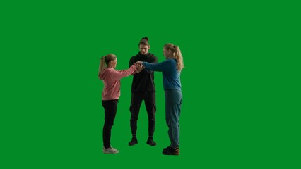 A group of hikers of three people put their hands together in a lock, laying a hand on each other's arm. Tourist team in the studio on the green screen in full height. Travel concept, teamwork.