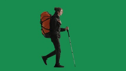 Tourist traveling using trekking poles on a hike. Full length man with backpack on his back walking on green screen. The concept of hiking. Side view.