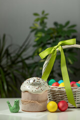 traditional Orthodox Easter cake and colored eggs in a wicker basket, on a white table in the middle plan. happy Easter