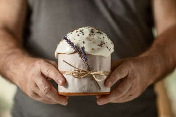 traditional Orthodox Easter cake, in men's hands, close-up on a dark background. happy Easter