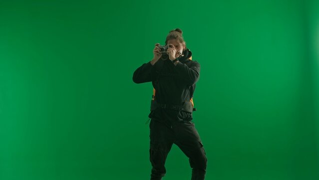 A male traveler takes pictures with a camera while hiking. Man hiker in studio on green screen. Concept of travel, active rest, hiking.