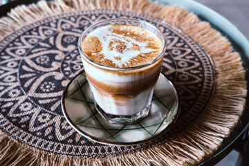 A close up of iced coffee cappuccino. Cups of cappuccino or latte on on hand woven fabric background. Cosy coffee break concept. Flat-lay, top view.