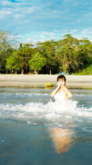 Splashing through the waves. Shot of laughing and smiling happiness asian women playing in wave at tropical beach.