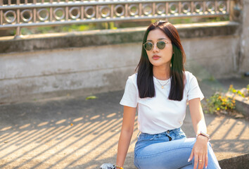 Fototapeta premium A beautiful young woman wearing a white shirt and glasses lies on the ground facing the camera, looking charming.