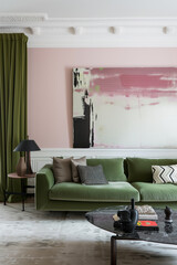 A modern living room with a stylish green sofa set against a backdrop of abstract art and pastel walls, accented by chic decorative elements