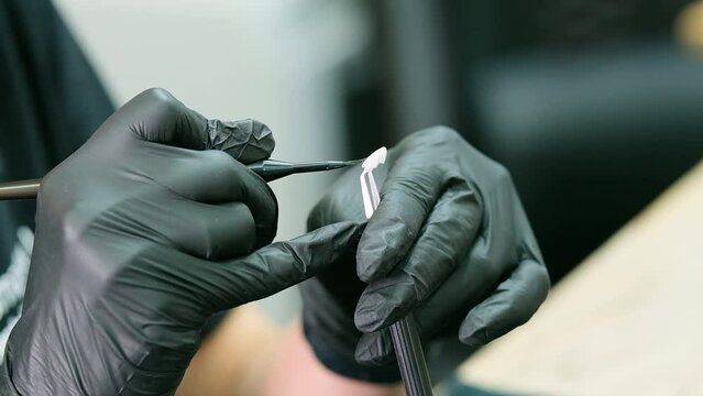 A dental specialist in black latex gloves paints veneers. Close-up.