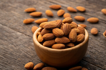 Dry roasted Almonds in wooden bowl on wooden table.Heap of almond.