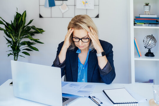 Shocked 50's mature businesswoman, middle-aged experienced female looking at documents in office. Accounting report. Frustrated worried face expression emotion feelings problem perception reaction.
