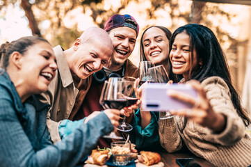 Group of young people taking selfie picture outdoor - Multiracial friends drinking and toasting red...