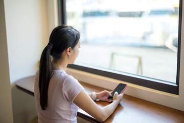 Woman use of mobile phone and sit inside the cafe