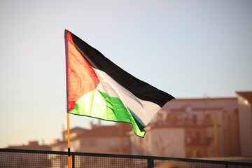 Palestinian flag flying freely in the suburban suburbs backlit at sunset