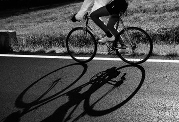 shadow of the cyclist on the racing bike on the road in backlight with dark and dramatic tones...