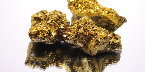 three golden stones on a white background over a mirror surface without people