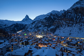 Panoramic landscape of Zermatt city Valley famous travel ski resort and iconic Matterhorn peak at dawn in the swiss alps, Switzerland. The snow covered village and church in Canton Valais in winter.