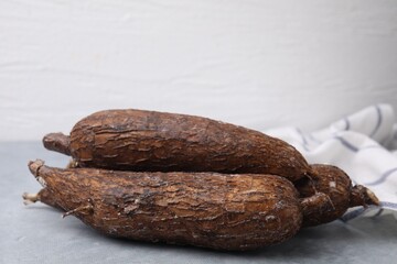 Fresh whole cassava roots on grey table, closeup