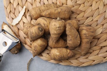 Tubers of turnip rooted chervil and peeler on gray table, top view