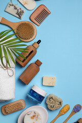 Flat lay composition with different spa products and tropical leaf on light blue background. Space for text