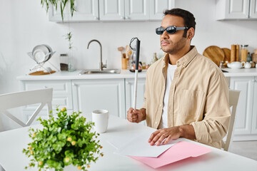 good looking indian blind man in cozy attire with glasses and walking stick reading braille code