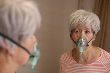 Senior woman using a breathing aid - obrazy, fototapety, plakaty