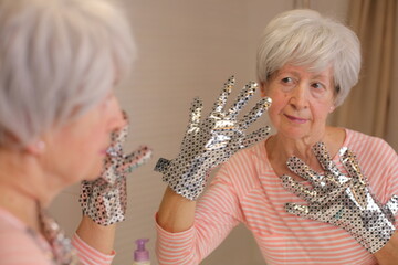 Senior woman using a hydrating therapy mask for her hands