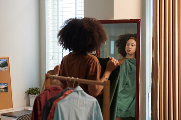Woman trying on clothes in front of mirror deciding what to wear for work