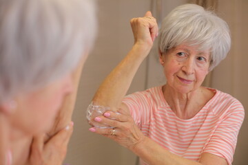 Senior woman moisturizing her dry elbows